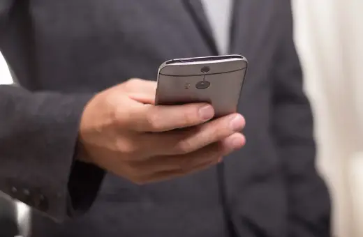 Mężczyzna w garniturze trzyma telefon, być może otrzymuje wiadomość o zawieszeniu działalności.