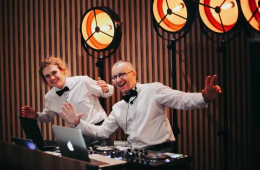 Dwóch DJ-ów w białych koszulach i czarnych muszkach, gotowych do zabawy. Zastanawiasz się, ile kosztuje dj na wesele?