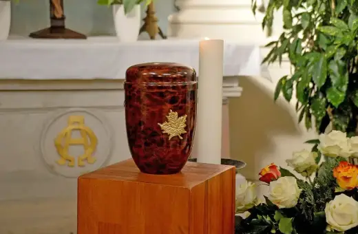 Elegancka, brązowa urna z liściem klonu, symbolizująca pamięć. To miejsce spoczynku prochów, co to urna.