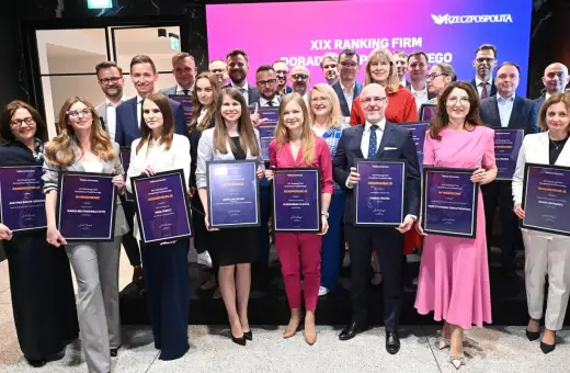 Grupa osób w eleganckich strojach pozuje z dyplomami na tle sceny z logo "Rzeczpospolita".