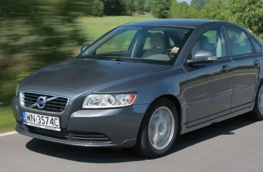 Szary Volvo S40 2.0 diesel w ruchu, z rozmytym tłem zieleni i drogi.