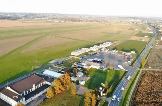 Lotnisko z hangarem i pasem startowym. W oddali widać pola i zabudowania. To miejsce, gdzie każdy wielki zwycięzca może wylądować.