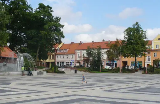 Dziecko biega po placu z fontanną, otoczonym kamienicami. To największy rynek w Polsce, tętniący życiem.