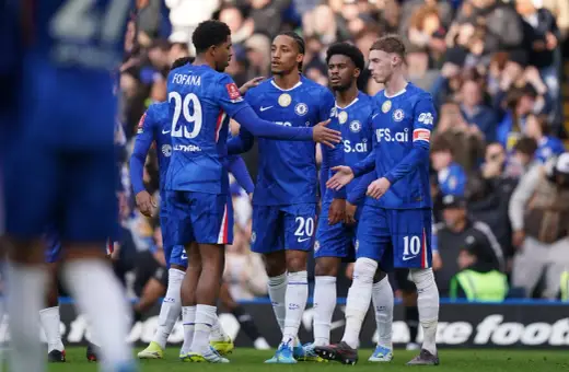 Piłkarze Chelsea w niebieskich strojach rozmawiają na boisku. Widać numery 29, 20 i 10.