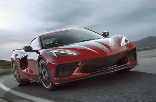 Czerwony Chevrolet Corvette C8 pędzi po drodze, jego sportowy design podkreślony przez dynamiczne linie i agresywny przód.