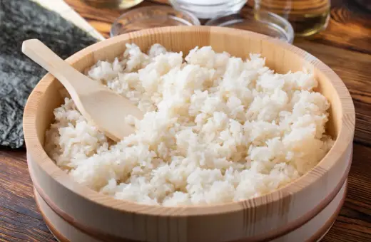 Idealny ryż do sushi, gotowy do przygotowania. Drewniana miska i łyżka sugerują tradycyjny sposób na to, jak ugotować ryż do sushi.
