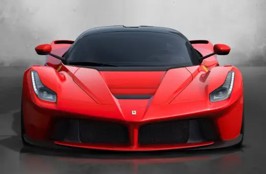 Przód czerwonego LaFerrari z czarnym dachem i przyciemnianymi szybami, błyszczący na tle szarej ściany.