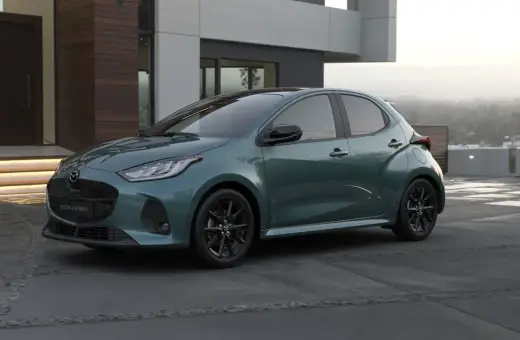 Elegancka, zielona Mazda 2 Hybrid stoi przed nowoczesnym domem.