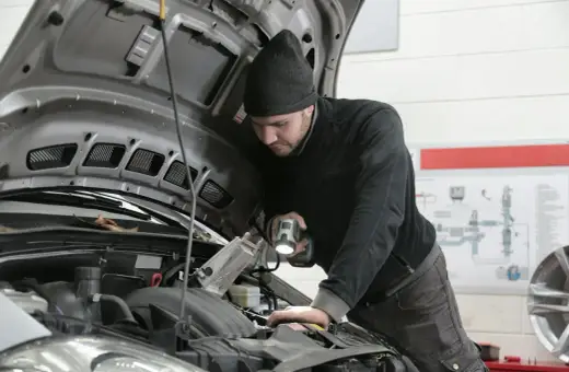 Mechanik z latarką bada silnik 1.6 TDI.