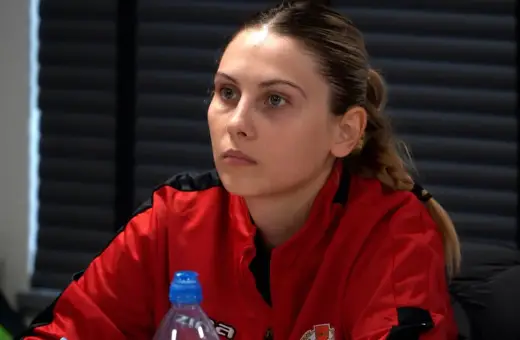 Młoda kobieta w czerwonej bluzie, przyszły trener UEFA A, słucha uważnie.
