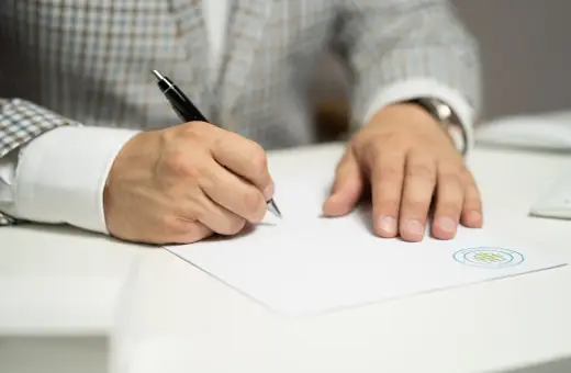 Mężczyzna w eleganckim garniturze podpisuje porozumienie zmieniające warunki pracy i płacy.