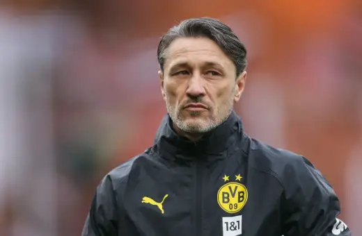 Kovac trener w czarnej kurtce z logo BVB, skupiony na boisku.