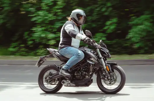 Motocyklista w kasku pędzi na czarnym Romet 125, pokonując kolejne 15 km.