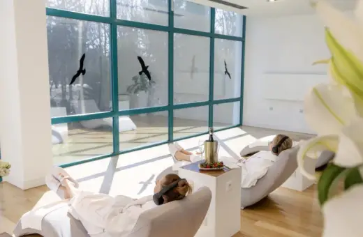 Relaks w spa, idealne **ciechocinek atrakcje na weekend**. Dwie kobiety w szlafrokach odpoczywają na leżakach, słuchając muzyki.