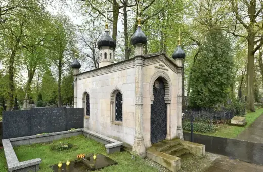 Kamienna kaplica z kopułami, ozdobnymi oknami i drzwiami, stanowi piękny grob.