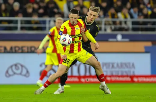 Piłkarz w żółto-czerwonej koszulce walczy o piłkę z rywalem w czarnym stroju. Intensywny przebieg: Pogoń Szczecin – Korona Kielce.