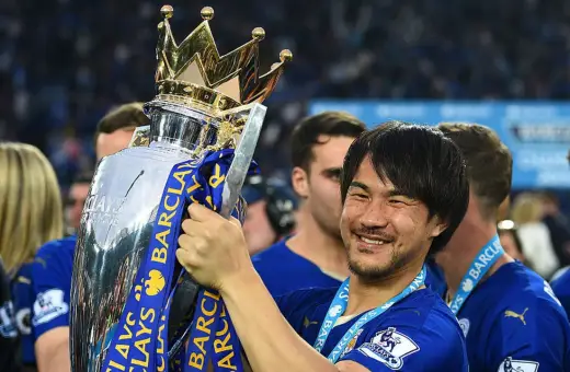 Shinji Okazaki z pucharem Premier League, uśmiechnięty, świętuje zwycięstwo.