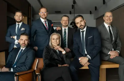 Grupa siedmiu profesjonalistów w garniturach, w tym jedna kobieta, pozuje do zdjęcia.
