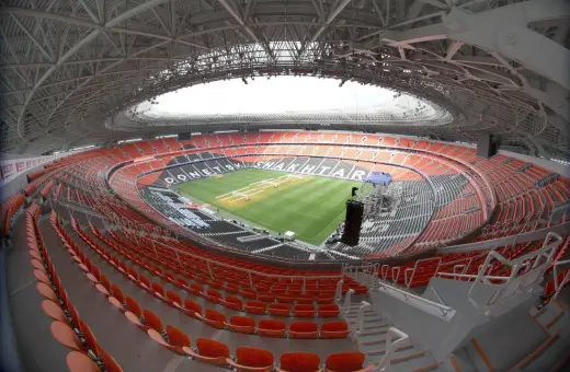 Pusta, nowoczesna arena stadionu Szachtara Donieck z pomarańczowymi i czarnymi siedzeniami oraz zieloną murawą.
