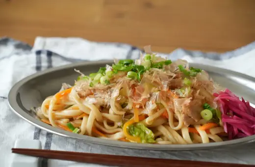 Udon z warzywami i szczypiorkiem, posypany płatkami katsuobushi. To właśnie katsuobushi co to jest, suszone płatki bonito, dodają daniu głębi smaku.