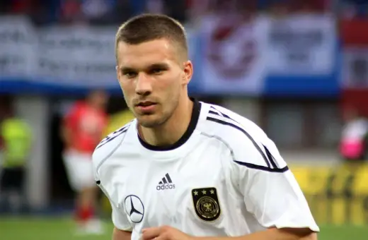 Piłkarz w białej koszulce reprezentacji Niemiec, z orłem i trzema gwiazdkami. To młody Podolski, gotowy do gry.