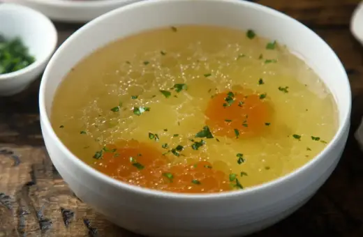 Aromaticzny rosół z perliczki, bogaty w smaku, z kawałkami marchewki i posypany natką pietruszki. Idealny na chłodne dni.