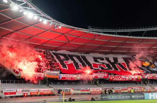 Tłum kibiców, ultrasi, tworzy morze czerwonego dymu i ognia, rozwijając ogromny transparent "POLSKA".