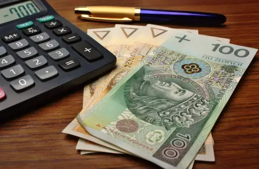 Kalkulator, długopis i polskie banknoty, w tym 100 zł. Przygotowanie do rozliczenia karty podatkowej.