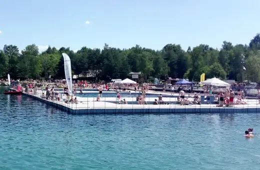 Słoneczny dzień na Balatonie w Trzebini. Ludzie odpoczywają na pływającym pomoście i w wodzie.