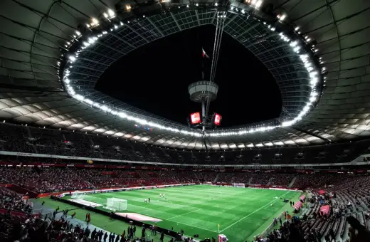 Widok na murawę i trybuny największego stadionu w Polsce. Rozświetlony dach i jupitery tworzą niesamowitą atmosferę.