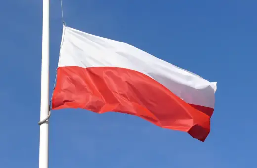 Biało-czerwona flaga Polski powiewa na maszcie na tle błękitnego nieba. Czy żałoba jest obowiązkowa?