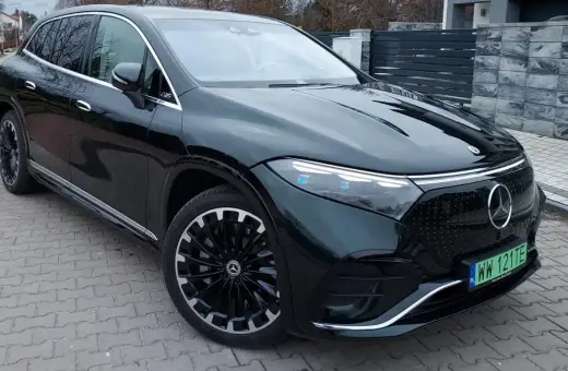 Elegancki, ciemnozielony Mercedes EQS SUV z nowoczesnymi światłami i felgami stoi na podjeździe.