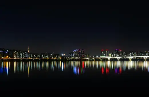 Nocny widok na Seul z rzeką Han, mostem i wieżą Namsan. Światła miasta odbijają się w wodzie, tworząc magiczny krajobraz. Itaewon tętni życiem.