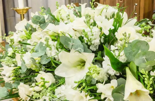 Piękna, biała wiązanka kwiatów z liliami, różami i zielonymi liśćmi.