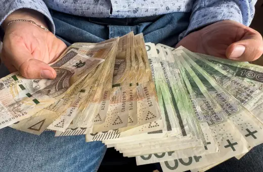 Ręce trzymające stos banknotów 100 zł i 200 zł. To darowizna od rodziców na nowy cel.