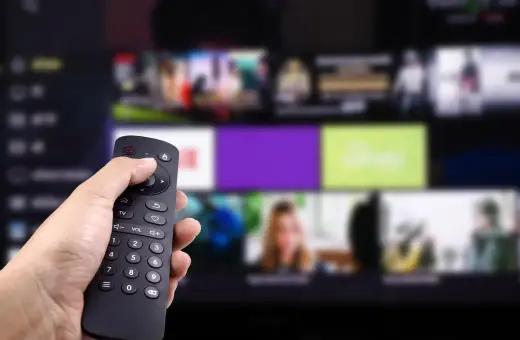 Dłoń trzyma pilot, wybierając program. Zastanawiasz się, kto jest zwolniony z abonamentu RTV? Może Ty?