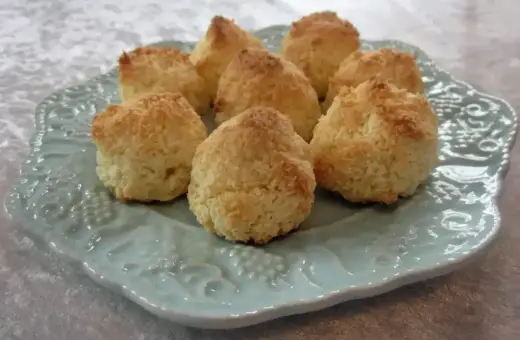 Små, gyllene kokostoppar på en vacker ljusblå tallrik. Perfekt för ett enkelt kokostoppar recept.