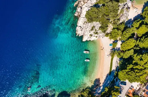 Chorwacja gdzie na wakacje? Rajska plaża z krystalicznie czystą wodą, łódkami i zielonymi wzgórzami. Idealne miejsce na relaks.