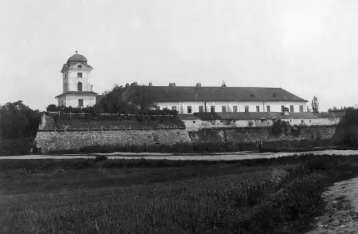 Zamek w Rzeszowie z wieżą i długim budynkiem, otoczony kamiennym murem.
