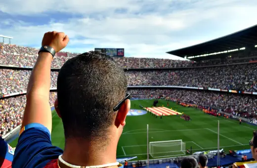 Kibic z podniesioną pięścią na stadionie, dumny jak właściciel Barcelony.