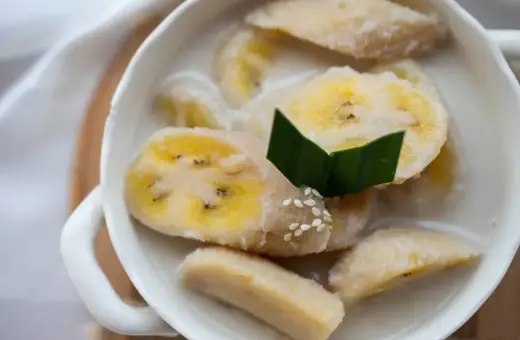 Kawałki banana w mleku kokosowym, ozdobione liściem pandanu i sezamem. Pyszny tajski deser.