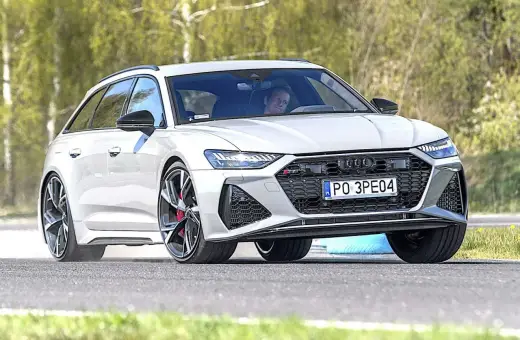 Białe Audi RS6 Avant na torze, kierowca wpatrzony przed siebie.