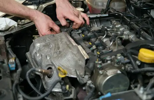 Mechanik pracuje przy silniku, wymieniając czujnik położenia wałka rozrządu.