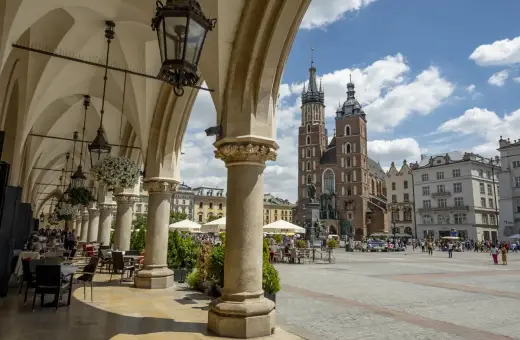 Podcienia Sukiennic w Krakowie, z widokiem na Rynek Główny i Kościół Mariacki. Stare miasto kraków tętni życiem.