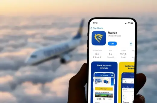 Ręka trzyma smartfon z aplikacją Ryanair, gotową do odprawy online. W tle samolot leci nad chmurami.