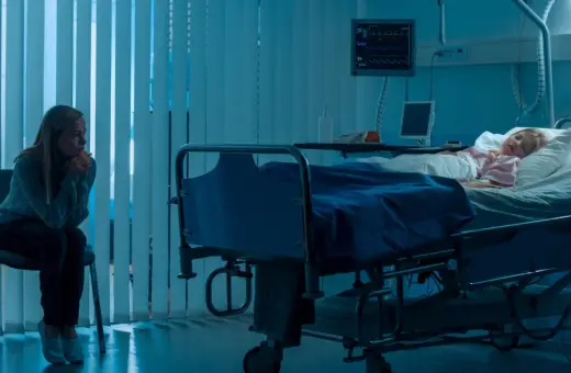 Zmartwiona matka siedzi przy łóżku chorej córki w szpitalu. Scena sugeruje zespół Münchhausena u matek, gdzie matka może wywoływać objawy u dziecka.