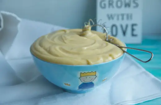 Gładki, kremowy krem patissiere w niebieskiej miseczce z małym królem. Idealny do deserów.