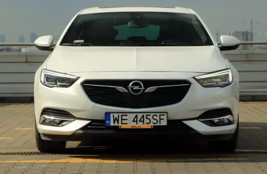 Biały Opel Insignia 2.0 Turbo z polskimi tablicami WE 445SF zaparkowany na dachu.
