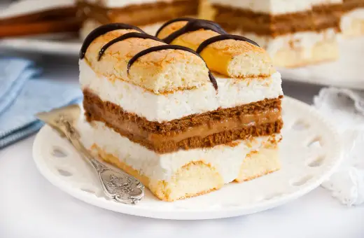 Szybkie ciasto z serkiem mascarpone, przełożone kremem i biszkoptem, ozdobione czekoladą. Idealne na deser.