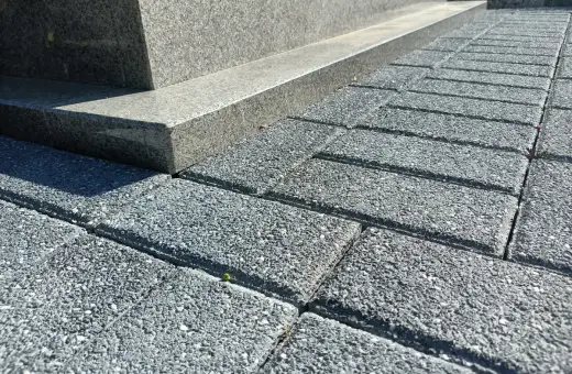 Szare kostki brukowe tworzą ścieżkę wokół pomnika. Idealne, by położyć wokół pomnika, tworząc schludne i trwałe otoczenie.